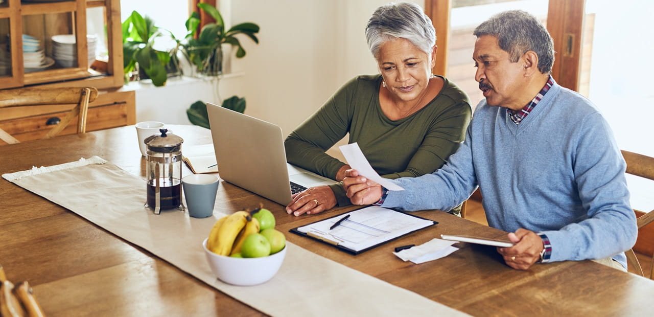 Woman and man sit at dining room table reviewing financial statements