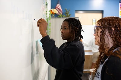 Students solve match problems on a white board